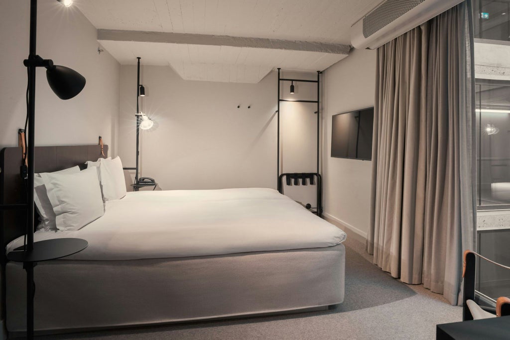 Modern Scandinavian hotel room with minimalist design, crisp white linens, elegant wooden furniture, and soft natural lighting from large windows.