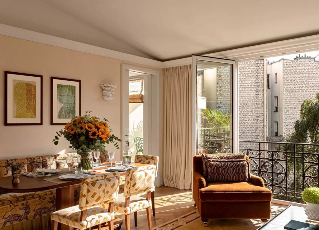 Opulent Parisian hotel suite with gold-accented red velvet walls, crystal chandelier, antique furnishings and floor-to-ceiling windows