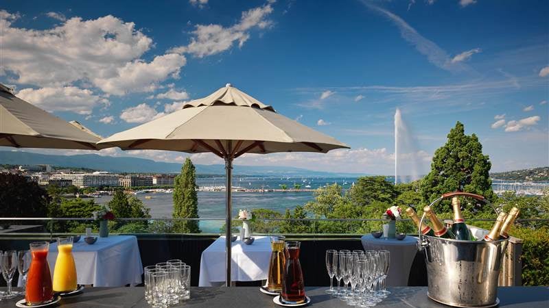 Historic luxury hotel in Geneva featuring Belle Époque architecture with elegant stone façade, ornate balconies and iconic golden signage