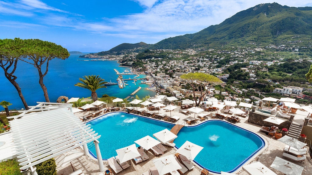 Elegant infinity pool overlooking the Bay of Naples merges with ocean horizon, surrounded by lush Mediterranean gardens at sunset