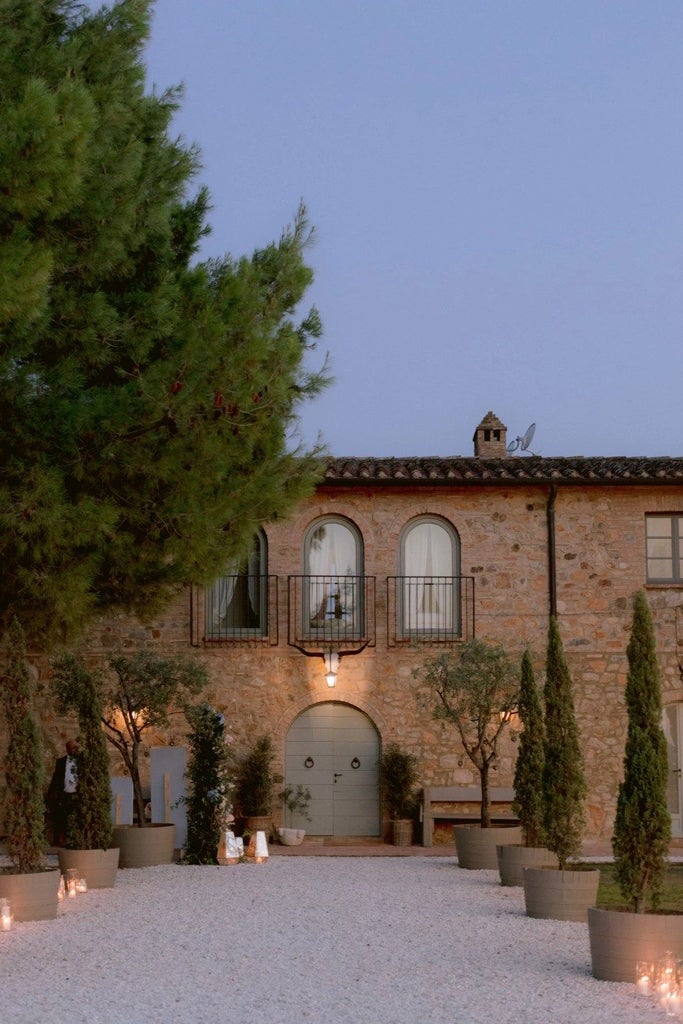 Luxurious Tuscan wine resort nestled among vineyards, with elegant stone architecture, rolling hills, and golden sunset casting warm light on the landscape