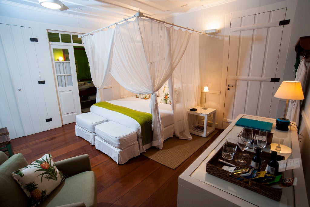 Elegant green-toned luxury suite at Casa Turquesa hotel, featuring lush tropical decor, plush white bedding, and refined Brazilian interior design elements