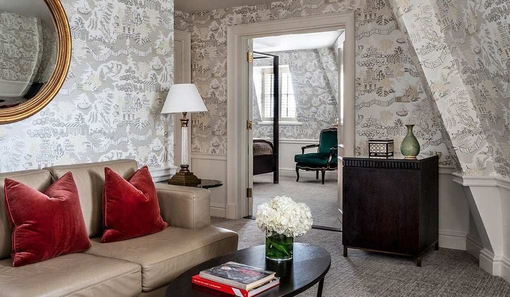 Opulent hotel suite with king-sized bed, plush white linens, dark wood furnishings, and city view through large windows in United Kingdom