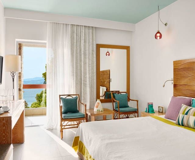 Luxurious double room with panoramic Aegean Sea view, elegant white interiors, spacious balcony, and plush furnishings at Eagles Palace hotel in Greece