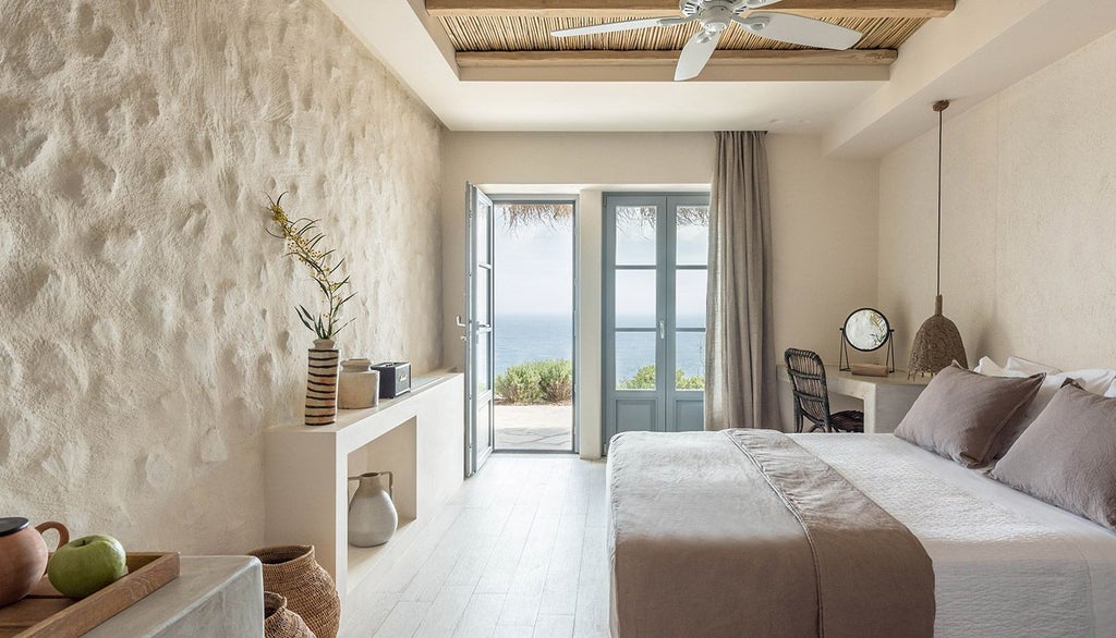 Minimalist white-washed Greek hotel room with elegant blue accents, panoramic Aegean Sea view, sleek modern furniture, and soft natural lighting