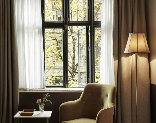 Elegant boutique hotel in Copenhagen featuring classical facade with arched windows, wrought-iron balconies and ivy-covered walls