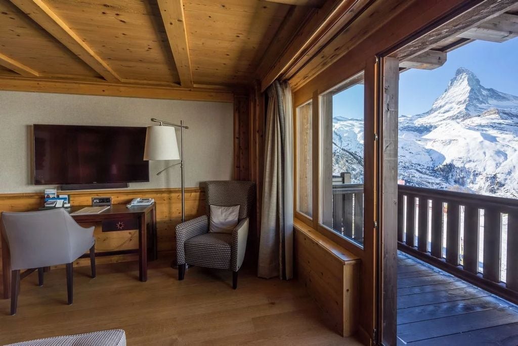 Elegant mountain resort with wooden balconies nestled in snow-capped Swiss Alps, featuring traditional chalet architecture at sunset