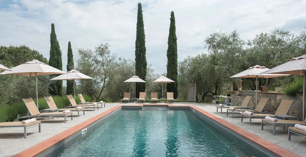 Elegant Tuscan villa with stone facade, terracotta roof, and manicured gardens, overlooking rolling countryside near Val d'Orcia, radiant with golden sunlight