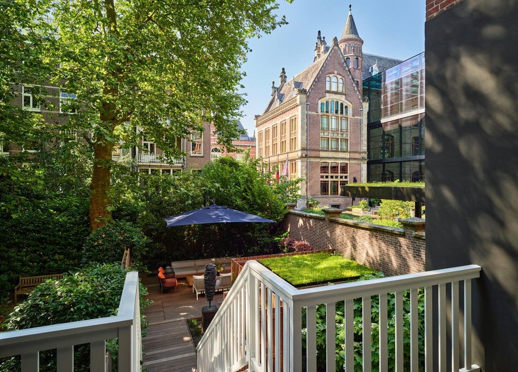 Luxurious garden-view suite with modern design, featuring floor-to-ceiling windows, elegant furnishings, and natural light in Amsterdam's Conservatorium Hotel