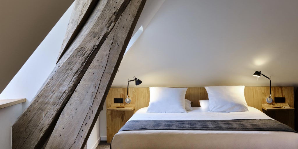 Luxurious minimalist hotel room with white walls, elegant modern furniture, large windows overlooking French countryside near Chablis vineyards