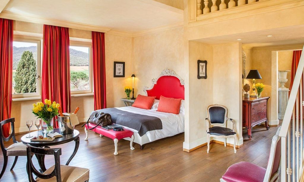 Elegant superior room at L'Andana, Tuscany, with plush king bed, soft neutral tones, rustic wooden furniture, and soft natural light streaming through large windows