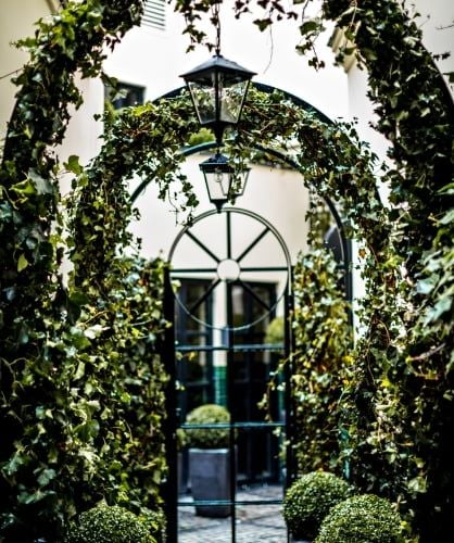 Elegant 5-star hotel facade in Paris with chic Art Deco styling, featuring charcoal gray exterior, ornate balconies, and sophisticated French architectural details