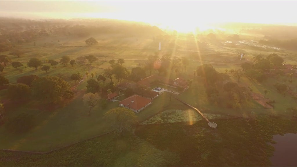 Luxury eco-lodge nestled in Brazilian Pantanal, wooden cabins amid lush wetlands, sunset casting golden light on serene wildlife sanctuary