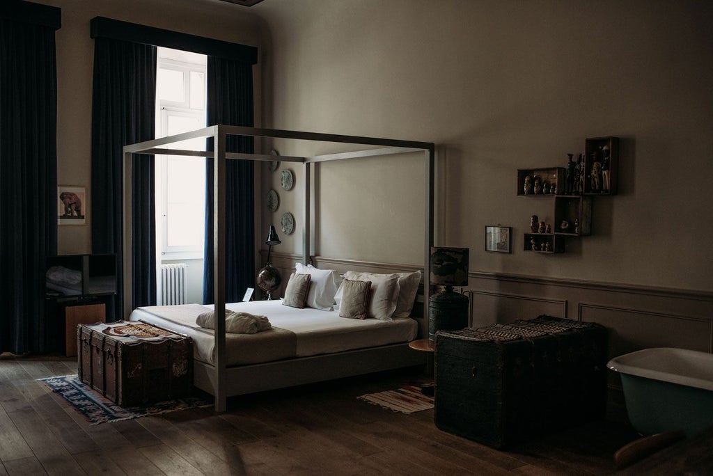 Elegant Florentine deluxe suite with antique furnishings, exposed wooden beams, plush white bedding, and warm terracotta-toned walls