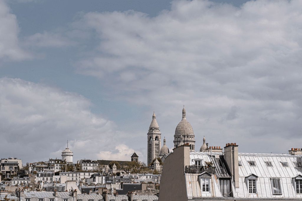 Elegant, art deco-inspired boutique hotel in Paris with soft pink facade, vintage decor, and chic Parisian streetscape in the background.