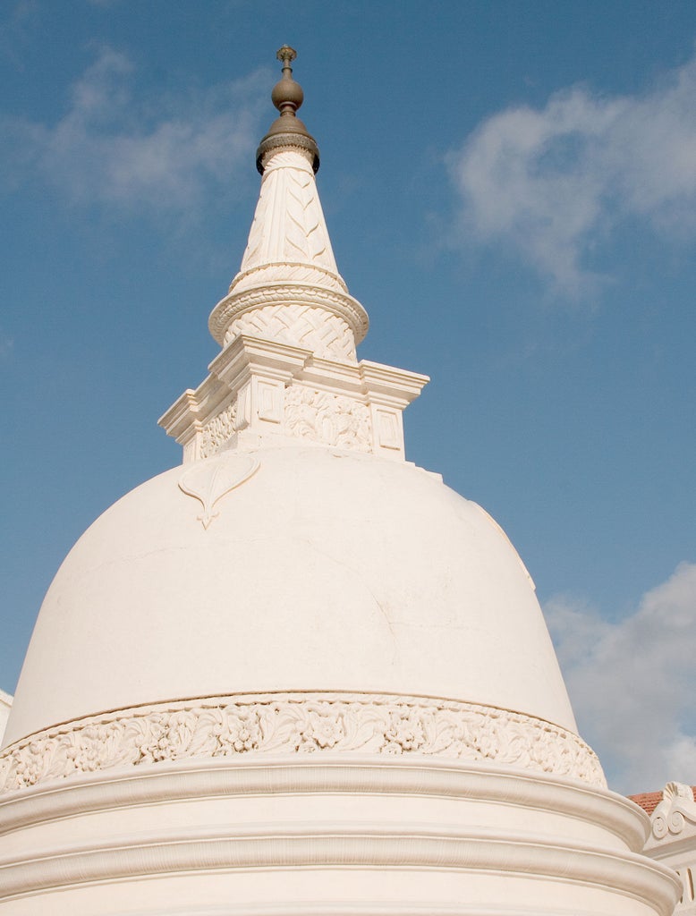 Grand colonial building with white facade, tall palm trees and lush gardens, showcasing Amangalla's historic Dutch architecture in Galle, Sri Lanka