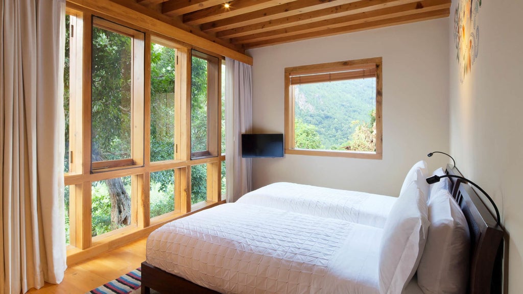 Luxurious COMO Villa bedroom in Punakha, Bhutan, with elegant wood furnishings, traditional architecture, and panoramic mountain valley views through large windows.