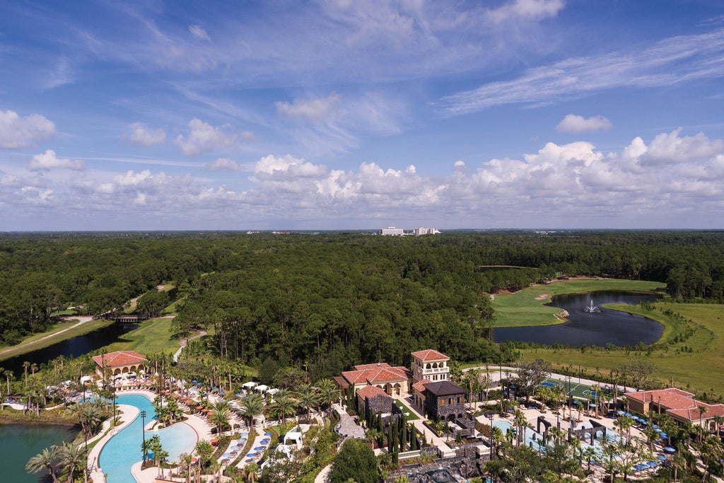 Elegant Four Seasons Orlando resort exterior with grand entrance, palm trees, and marble fountain reflecting golden evening light