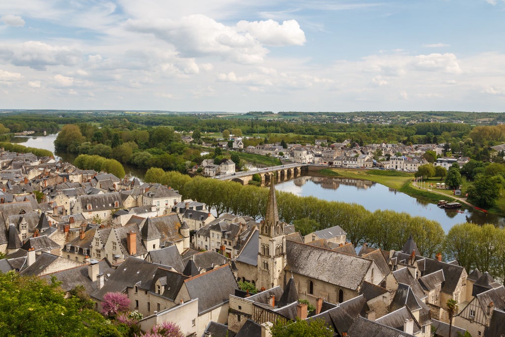 Loire Valley sunset over elegant château with manicured French gardens, vineyards, and ornate fountains along winding river