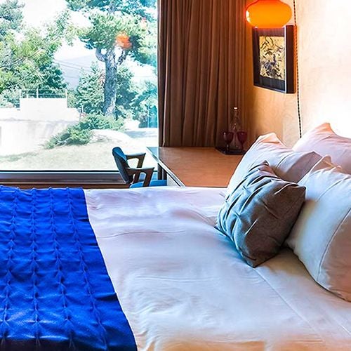 Elegant mountain-view double room at Casa das Penhas Douradas, showcasing minimalist design with warm wooden accents and panoramic alpine landscape backdrop.