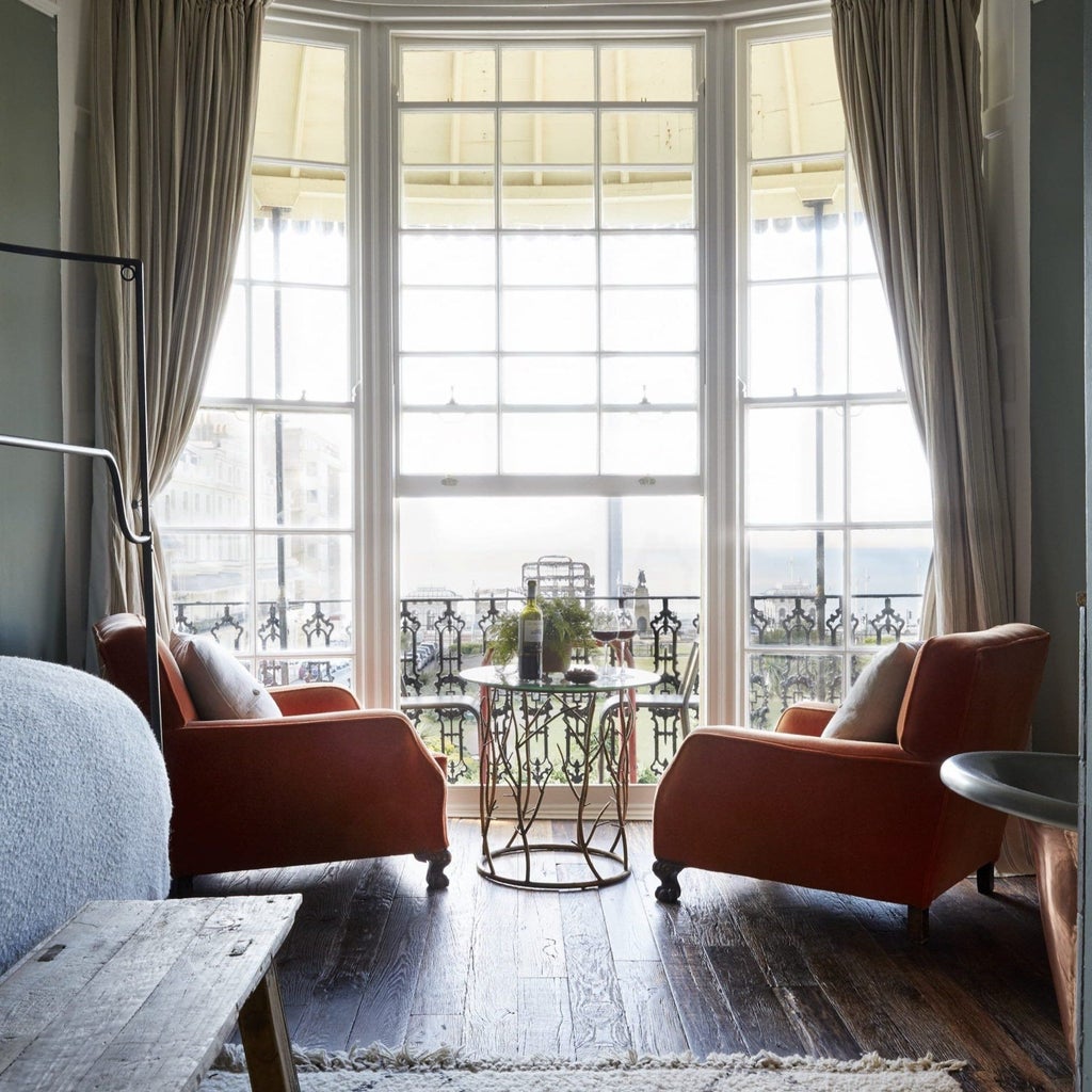 Boutique hotel exterior with elegant white facade, art deco details, and vibrant Brighton seafront backdrop, showcasing stylish urban luxury