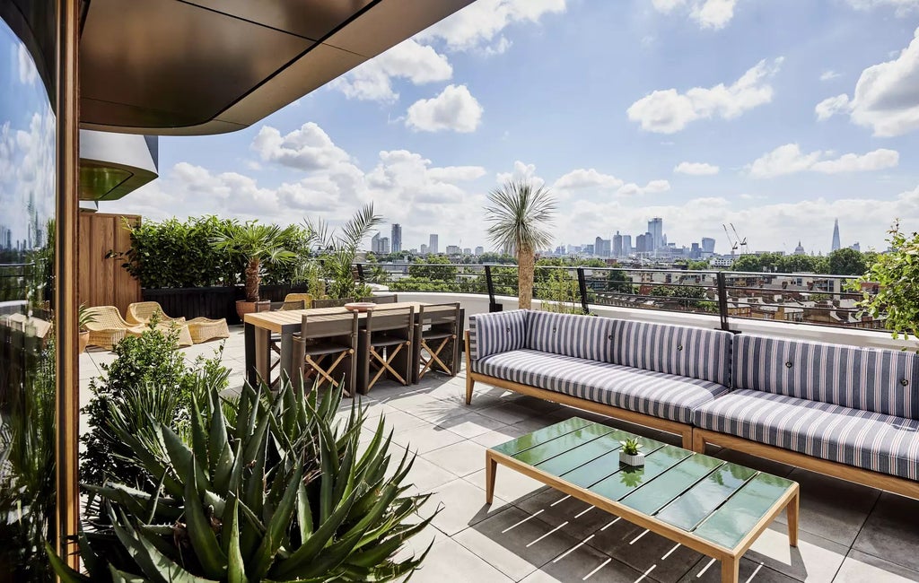 Luxurious rooftop terrace of contemporary hotel overlooking London skyline, featuring modern furniture and sweeping urban panoramic view at sunset