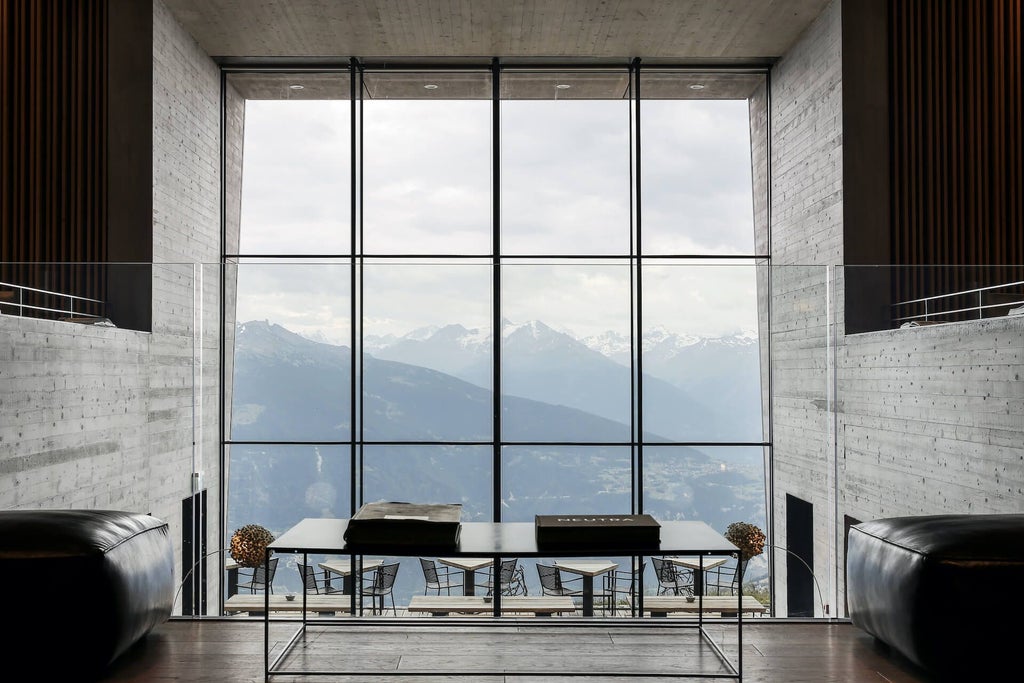 Luxurious alpine hotel Chetzeron perched on a rocky mountainside with panoramic Swiss Alps views, modern minimalist architecture blending with rugged landscape