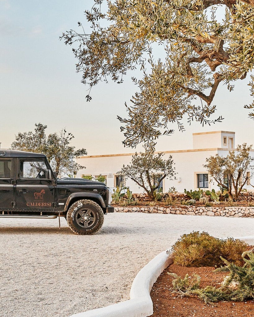 Rustic stone-walled luxury resort with terracotta tile roof, surrounded by olive groves and Mediterranean landscape in Puglia, Italy