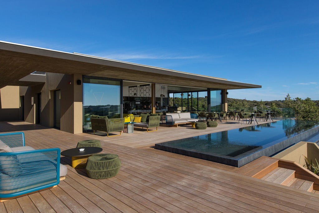 Modern luxury hotel nestled in Corsican mountains, featuring stone and glass architecture with panoramic views of Mediterranean coastline