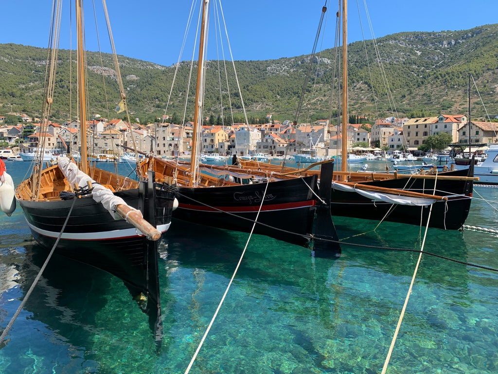 Sleek speedboat cruising along Croatia's turquoise coastline, passing rocky cliffs and hidden coves under clear blue summer skies