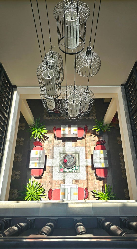 Luxurious boutique hotel facade with traditional Vietnamese architectural details, lush green plants, and warm ambient lighting at dusk in Hoi An