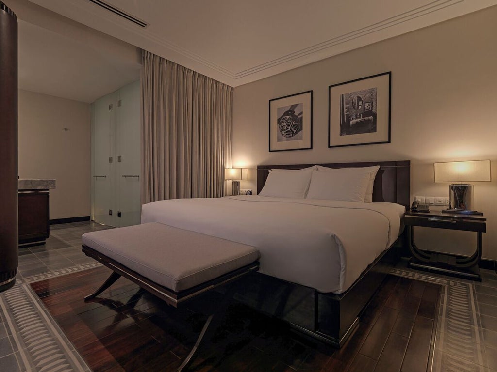 Elegant Deluxe Room at Azerai La Residence, featuring colonial-inspired decor, white walls, wooden accents, and plush king-sized bed with crisp linens in Hue, Vietnam