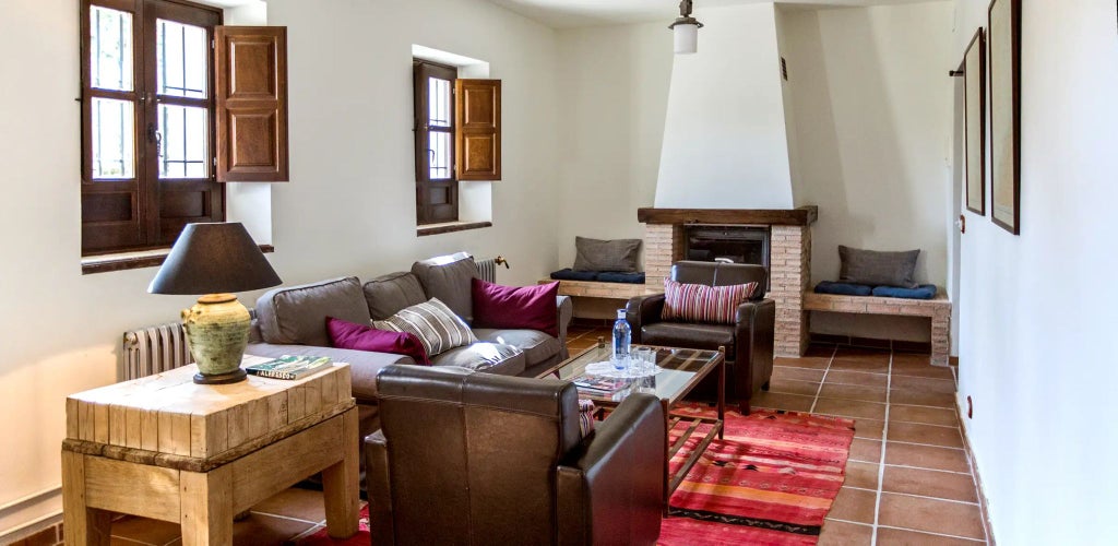 Elegant Spanish countryside hotel room with wooden-beamed ceiling, rustic white furnishings, and soft natural light illuminating traditional Los Olivos suite