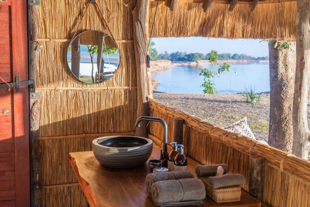 Luxurious safari lodge nestled in Zambia's remote wilderness, featuring tented canvas suites overlooking the Lower Zambezi River's pristine landscape