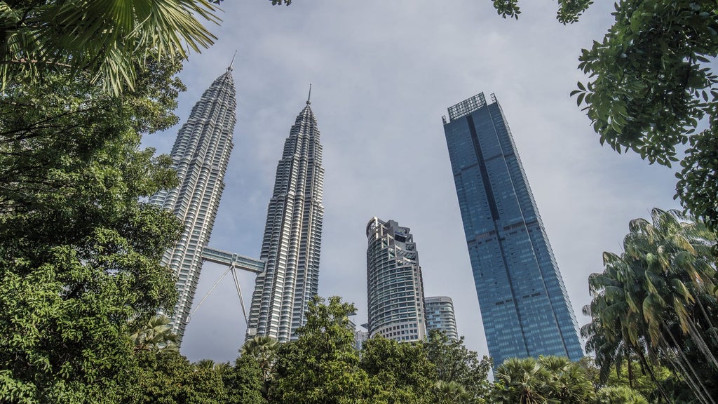 Sleek glass skyscraper of Four Seasons Kuala Lumpur rises against city skyline, featuring modern architecture and luxurious facade