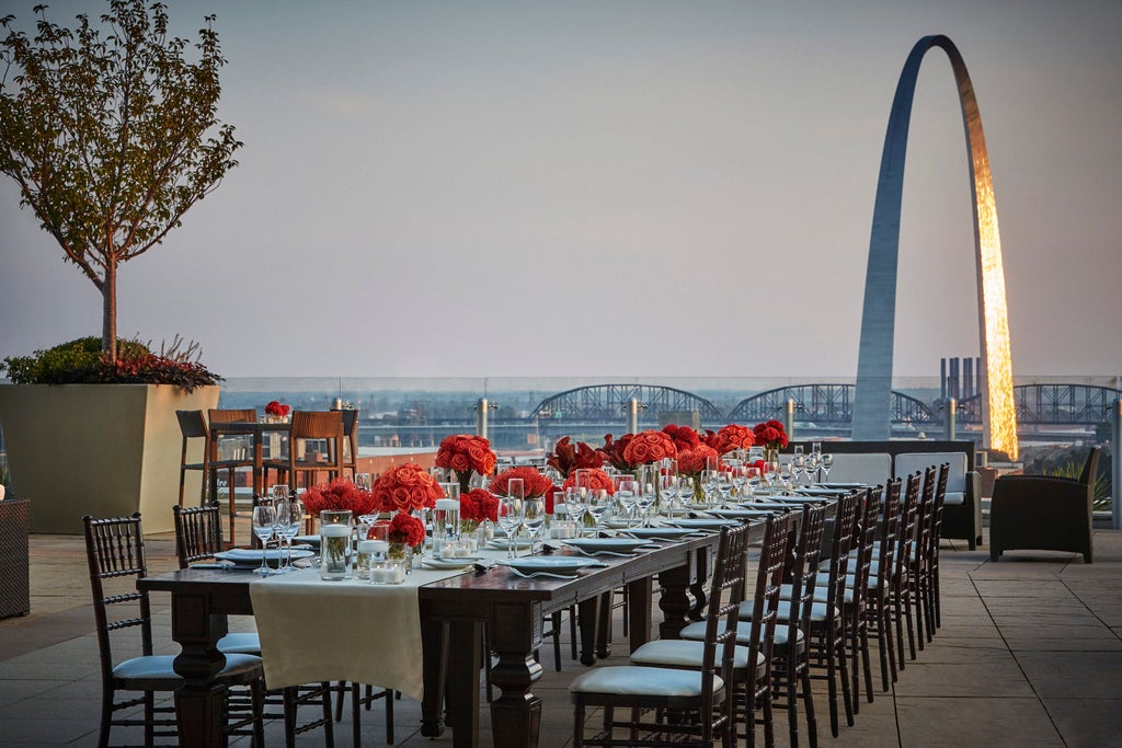 Contemporary glass hotel tower with infinity pool terrace overlooking St. Louis Arch and Mississippi River at golden hour