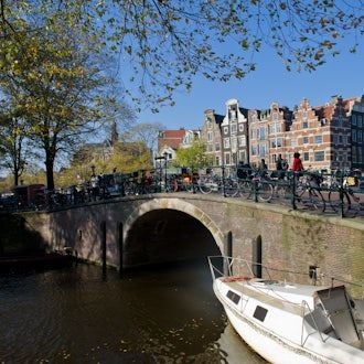 Elegant Canal House hotel nestled along Amsterdam's historic waterfront, featuring warm lighting, traditional Dutch architecture, and serene canal reflections at dusk