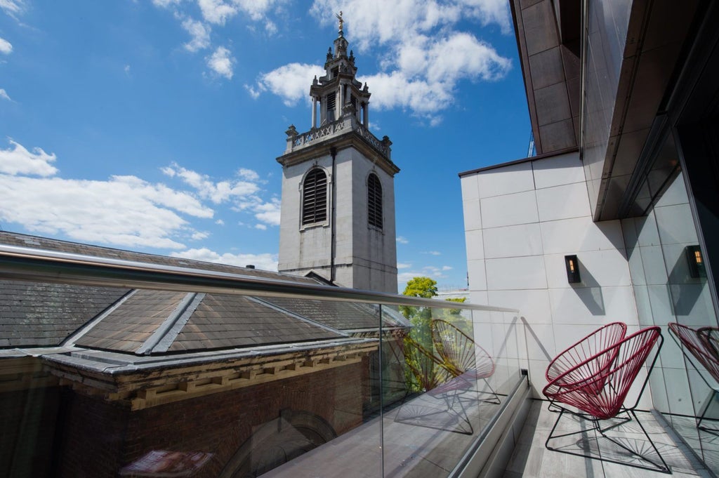 Elegant studio suite at Vintry & Mercer hotel, featuring plush king bed, contemporary design, warm wood tones, and city-view window in London's historic district