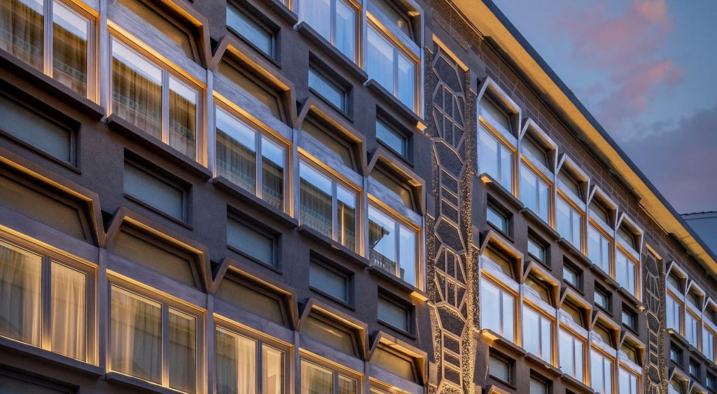 Modern luxury hotel facade in Florence with sleek architectural design, featuring glass windows, clean lines, and contemporary urban styling against a soft daylight backdrop.