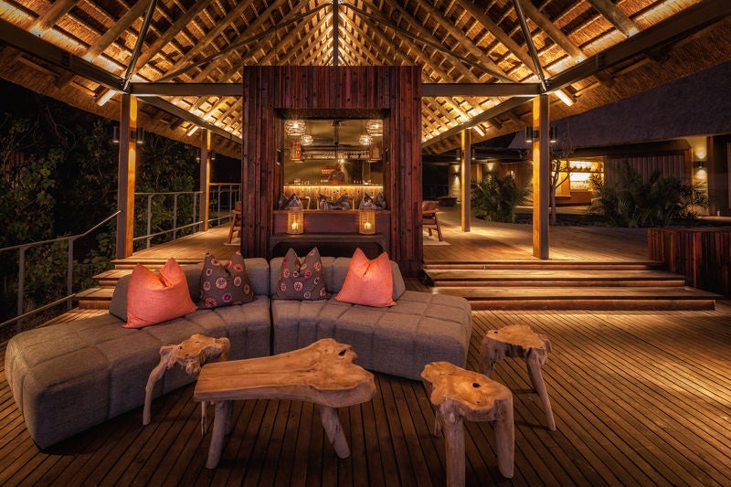 Elevated luxury safari lodge overlooking the Okavango Delta, featuring thatched roofs, wooden decks and natural-toned canvas tents