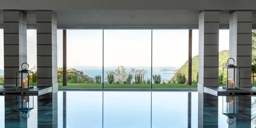 Infinity pool overlooking Lake Garda with loungers, surrounded by lush hills and mountains under a bright blue Italian sky