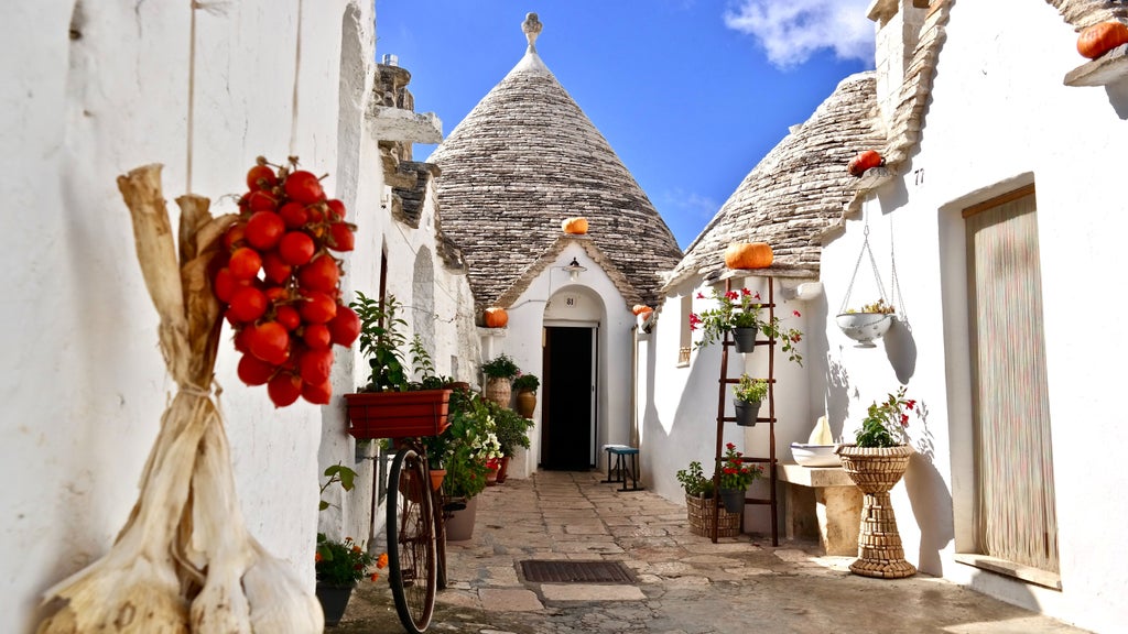 Traditional stone trulli houses with conical roofs amid olive groves in Puglia's Alberobello, bathed in warm Mediterranean sunlight