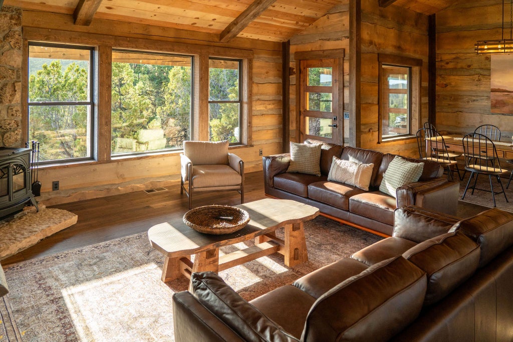 Rustic wooden lodge room with king bed, large windows overlooking mountain landscape, warm earth tones, and elegant southwestern-inspired decor at scenset Mountain Ranch