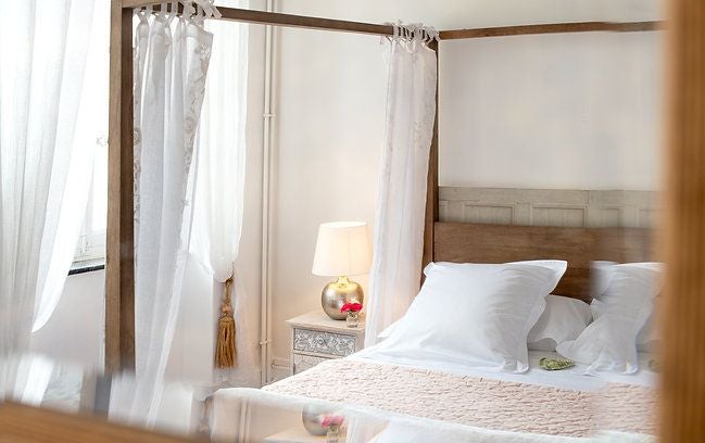 Elegant contemporary hotel room with white bedding, minimalist decor, warm wood accents, and soft natural light illuminating spacious French design aesthetic