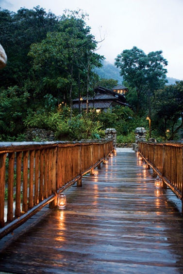 Luxurious stone cottage nestled in lush Peruvian cloud forest, with terra cotta roof and blooming orchids along rustic pathways