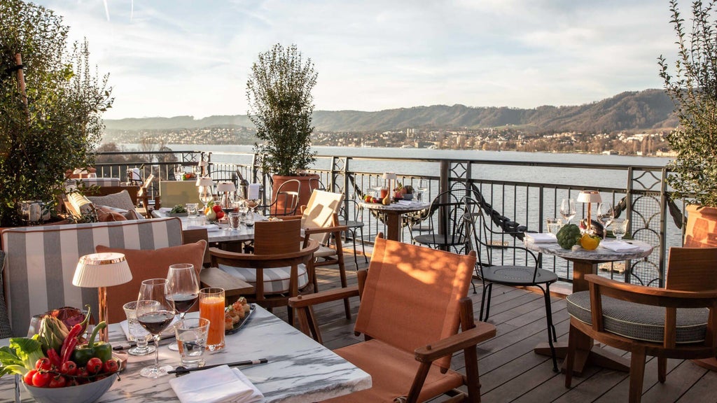 Luxurious lakeside hotel with elegant Swiss architecture, featuring panoramic views of Zurich's scenic waters and alpine landscape at sunset