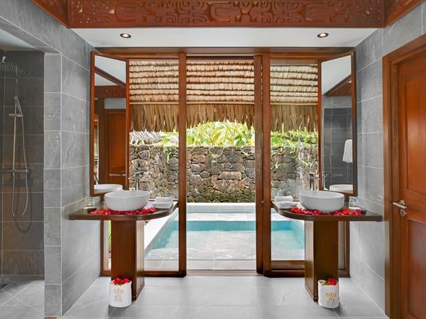 Luxurious overwater villa with private pool and deck overlooking turquoise Polynesian lagoon, surrounded by palm trees and coral gardens