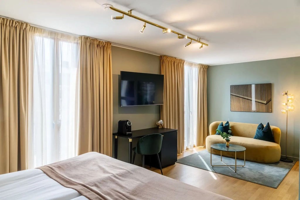 Elegant Stockholm hotel room with plush king bed, warm wood accents, soft gray textiles, and large windows overlooking city streetscape at golden hour