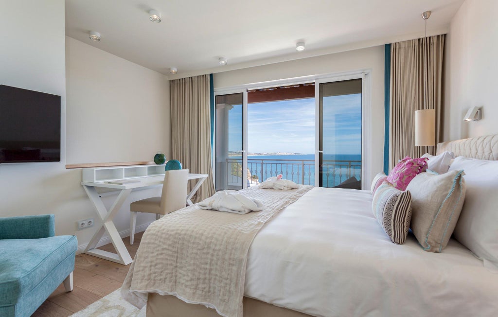 Elegant deluxe ocean view room at Vila Vita Parc Resort & Spa, featuring modern Portuguese design with pristine white decor and panoramic Atlantic coastline