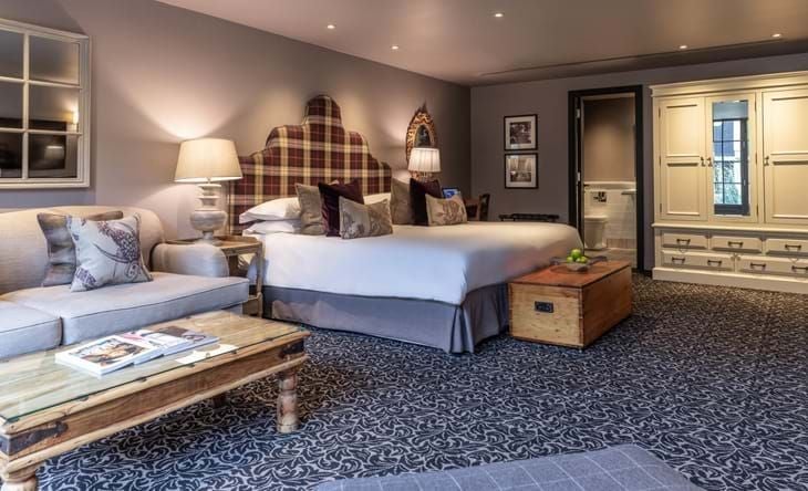 Spacious accessible suite with elegant courtyard view, featuring plush bedding, wooden floors, and modern furnishings in historic UK luxury hotel setting